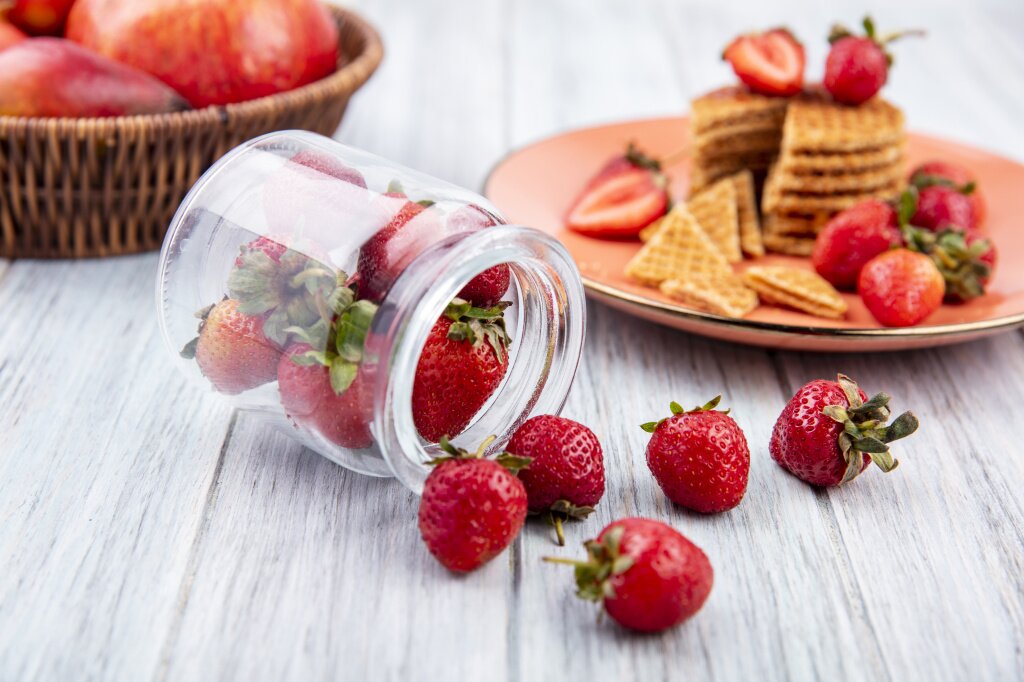 side-view-strawberries-spilling-out-jar-strawberry-cake-plate-with-fruits-wood.jpg