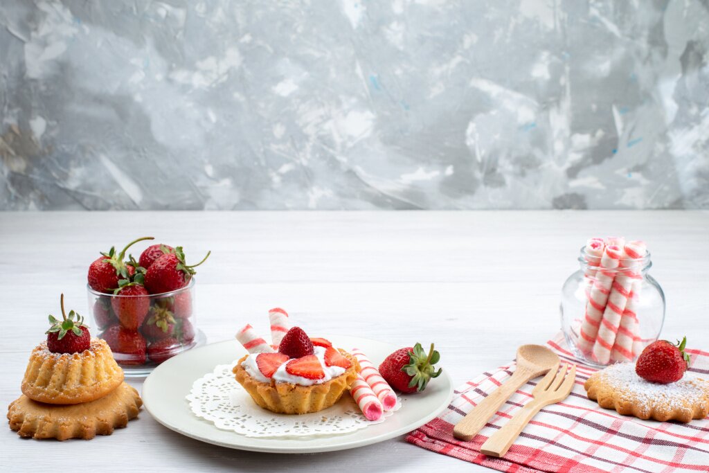 malen-kii-tort-so-slivkami-i-narezannoi-klubnikoi-torty-konfety-na-belom-stole-fruktovyi-tort-agodnyi-sahar.jpg