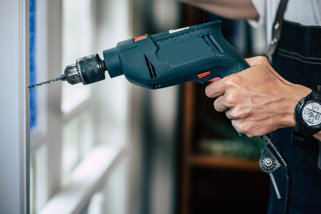 carpenter-holds-drill-drills-window.jpg