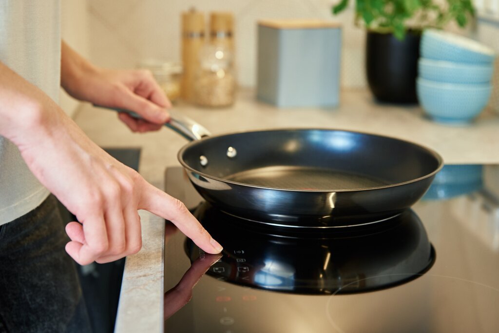 woman-turn-button-induction-stove-with-steel-frying-pan-kitchen-modern-kitchen-appliance.jpg