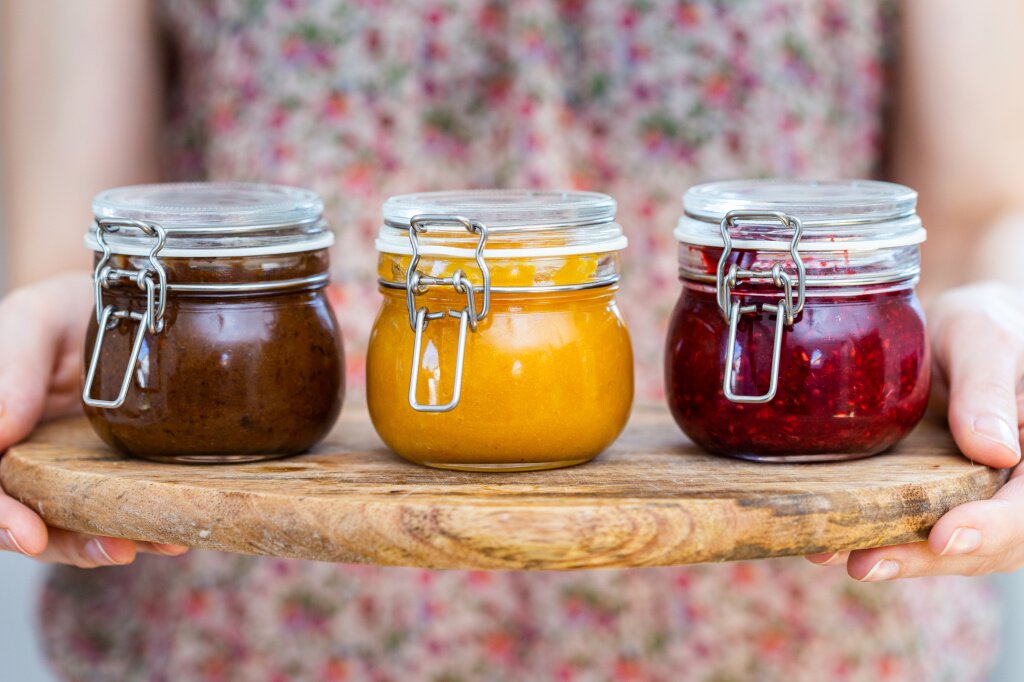 варенье closeup-view-woman-holding-wooden-plate-with-plum-apricot-raspberry-jam-glass-jars.jpg