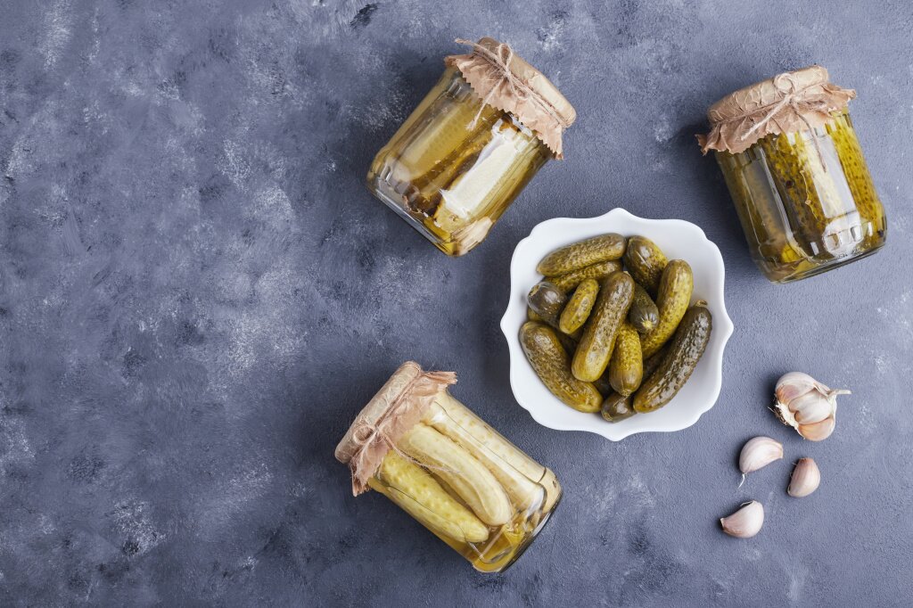 pickled-cucumbers-bowl-glass-jars-blue-background-with-garlic.jpg