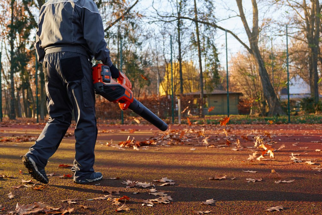 unrecognizable-man-working-with-handheld-leaf-blower-while-leaves-curling-glowing-around-back.jpg