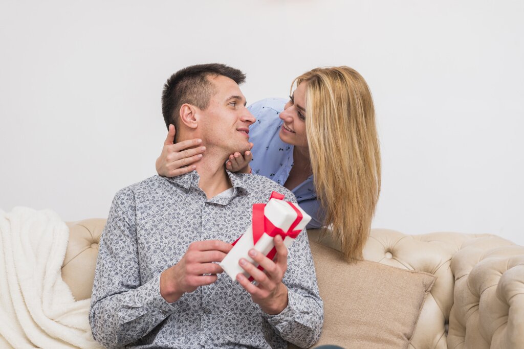 young-smiling-woman-looking-man-with-present-sofa.jpg