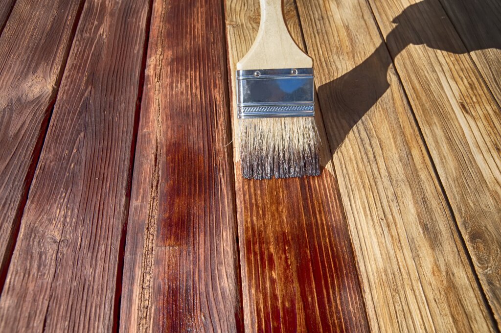кисть brush-covering-wooden-plank-surface-with-varnish.jpg